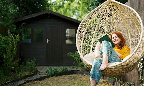 Woman sitting in a swing and smiling while reading a book.